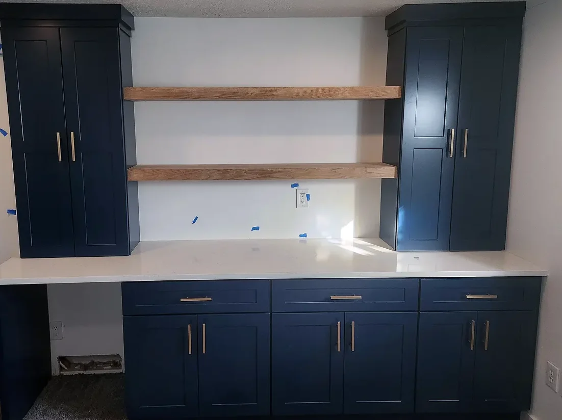 Basement craft room with built-in cabinets, shelving, and work surface for storage and projects