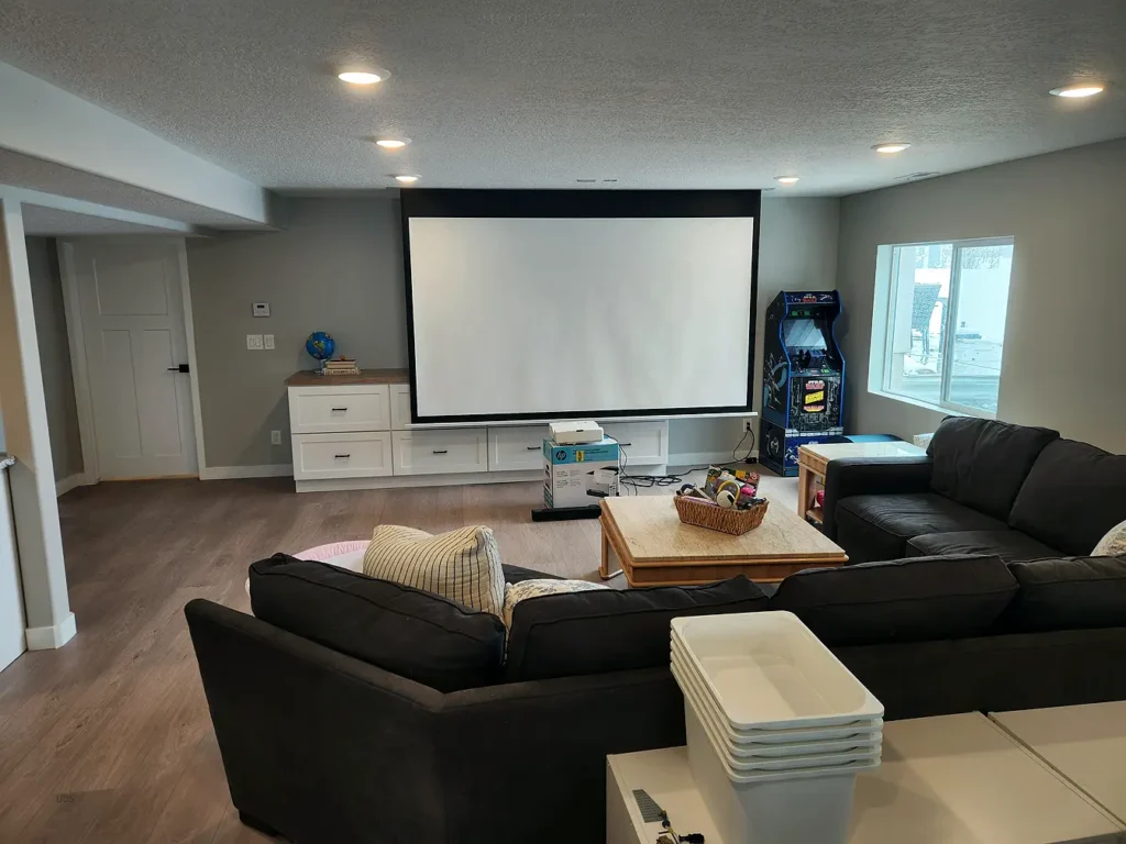 Finished basement living room with seating area and cieling mounted projector screen