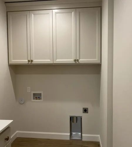Basement laundry room with upper cabinets and built-in storage for organization