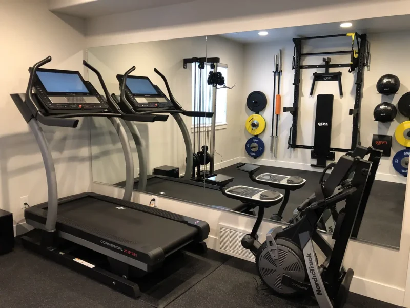 basement home gym with treadmill and weight equipment and wall mirror