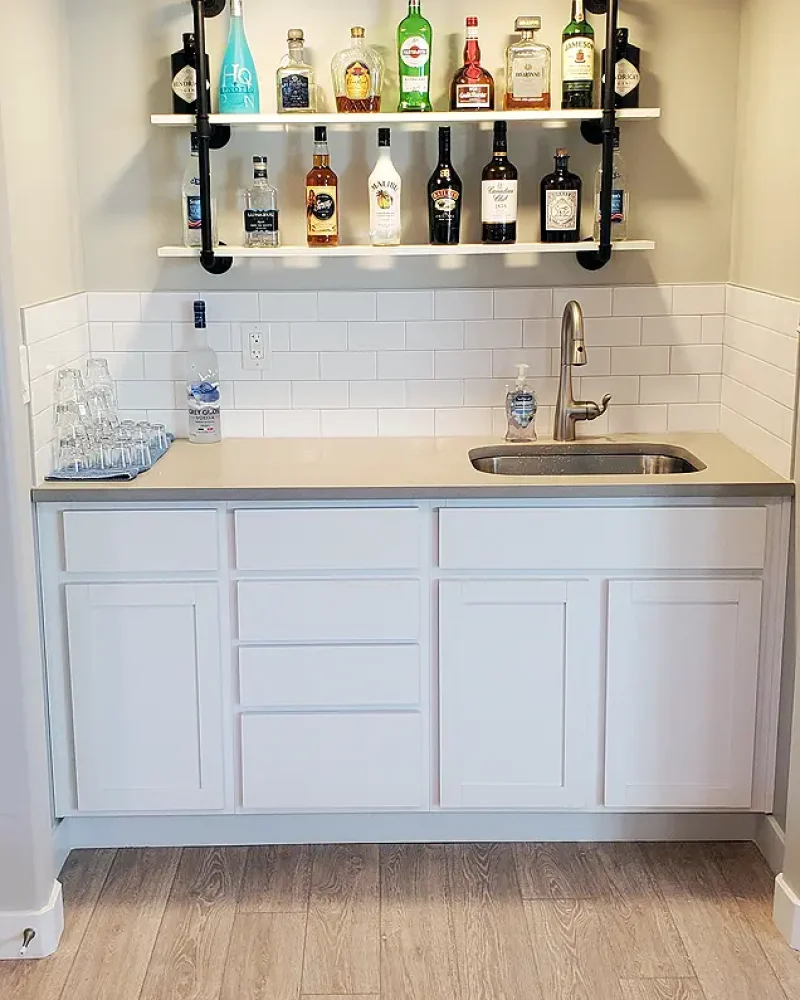 Utah Basement Finishing- a wet bar with white cabinets and a granite countertop