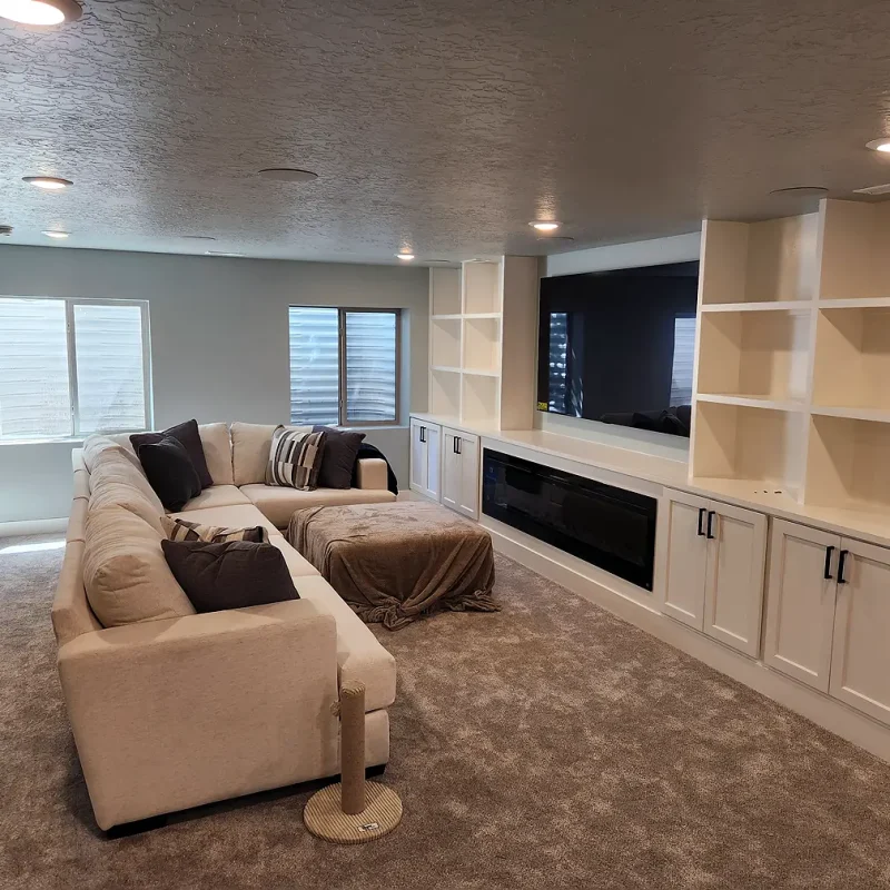 Basement Finishing Utah- a basement living room with a built in entertainment center and comfortable couches