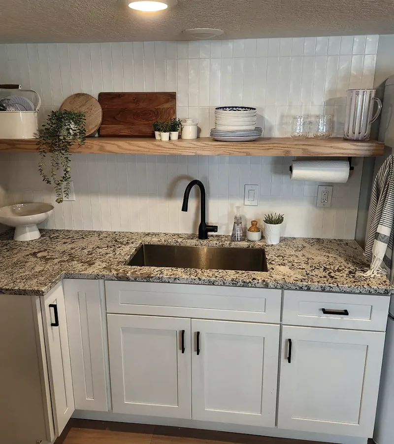 Basement Finishing Utah- a basement kitchen with white cabinets and a floating shelf