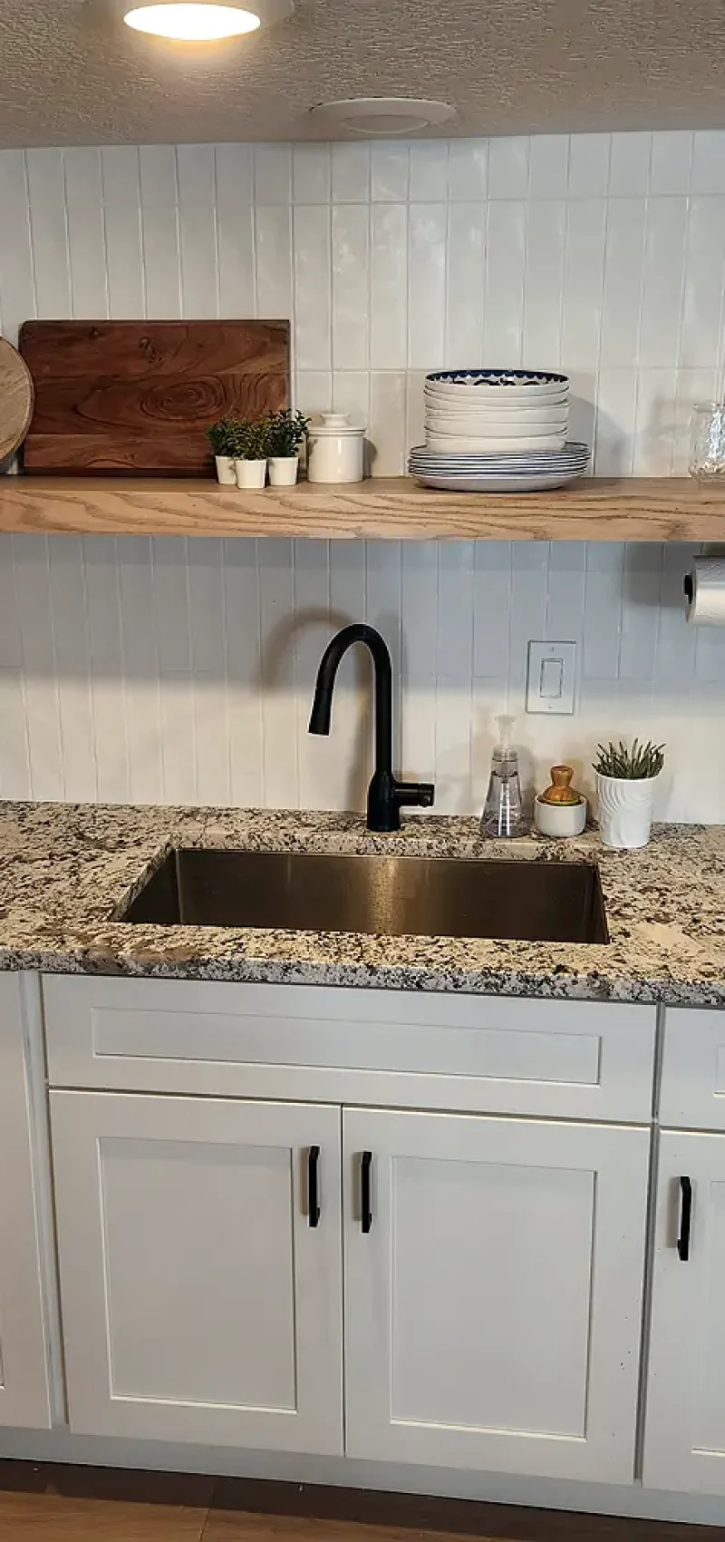 Basement Finishing Utah- a basement kitchen with white cabinets and a floating shelf